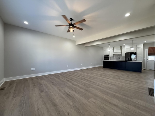 unfurnished living room with hardwood / wood-style floors, sink, and ceiling fan