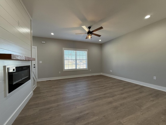 unfurnished living room with a fireplace, dark hardwood / wood-style floors, and ceiling fan