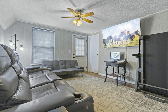 living room with ceiling fan, wood-type flooring, vaulted ceiling, and a textured ceiling