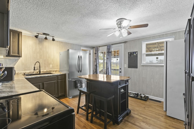 kitchen with sink, stainless steel refrigerator, white refrigerator, ornamental molding, and light wood-type flooring