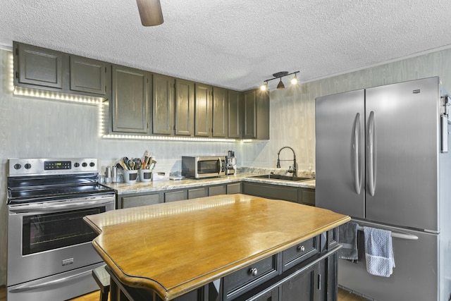 kitchen featuring a kitchen island, appliances with stainless steel finishes, sink, ceiling fan, and a textured ceiling