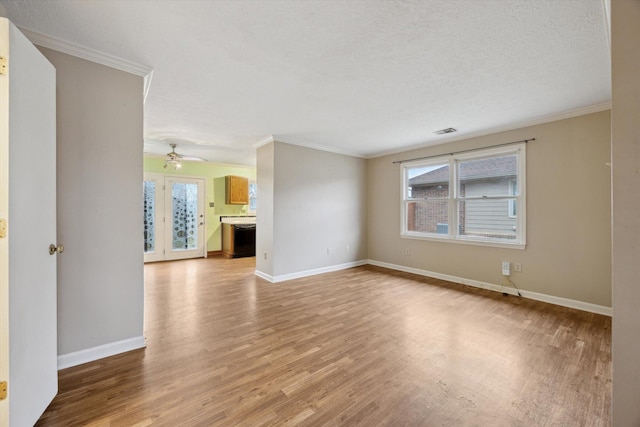 empty room with crown molding, a wealth of natural light, a textured ceiling, and light wood-type flooring