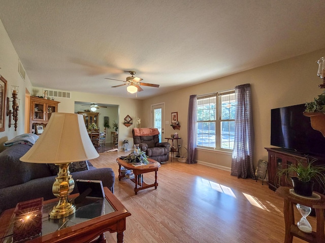 living room with a textured ceiling, light hardwood / wood-style floors, and ceiling fan