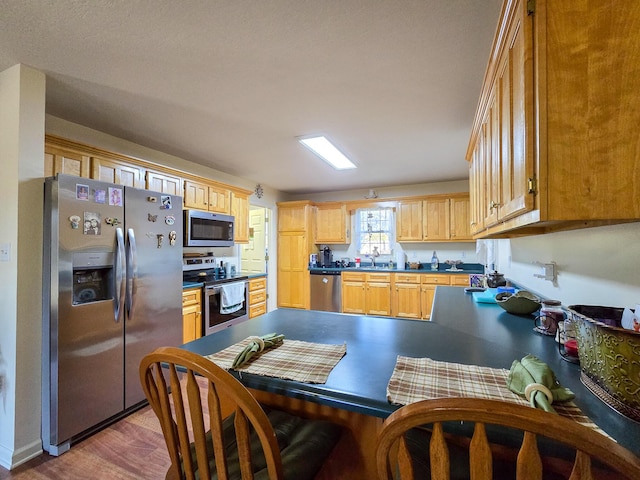 kitchen featuring light brown cabinetry, sink, wood-type flooring, and appliances with stainless steel finishes