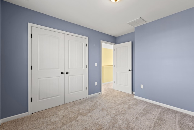 unfurnished bedroom featuring light carpet and a closet