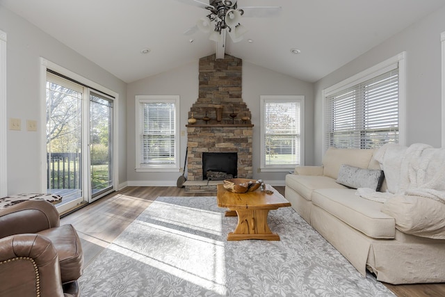 living room with ceiling fan, a fireplace, lofted ceiling with beams, and light wood-type flooring