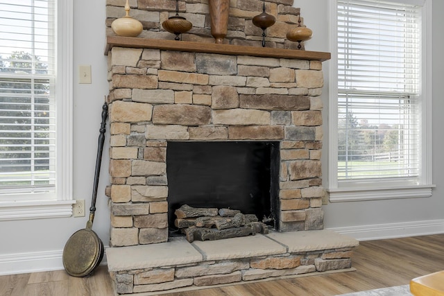 interior details with wood-type flooring and a stone fireplace