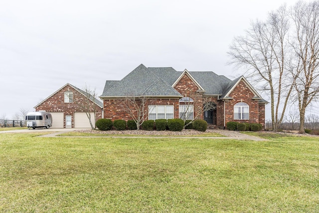 traditional home featuring a garage, brick siding, a front lawn, and roof with shingles