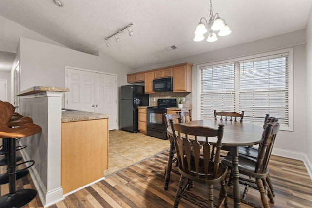 dining space featuring an inviting chandelier, vaulted ceiling, and wood-type flooring