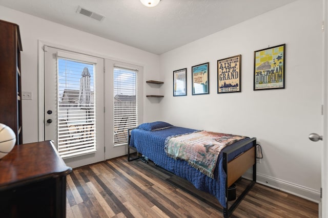 bedroom with access to outside, a textured ceiling, and dark hardwood / wood-style flooring