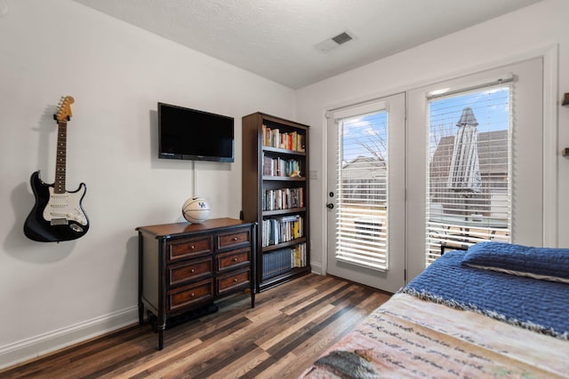 bedroom featuring access to exterior, dark hardwood / wood-style flooring, and a textured ceiling