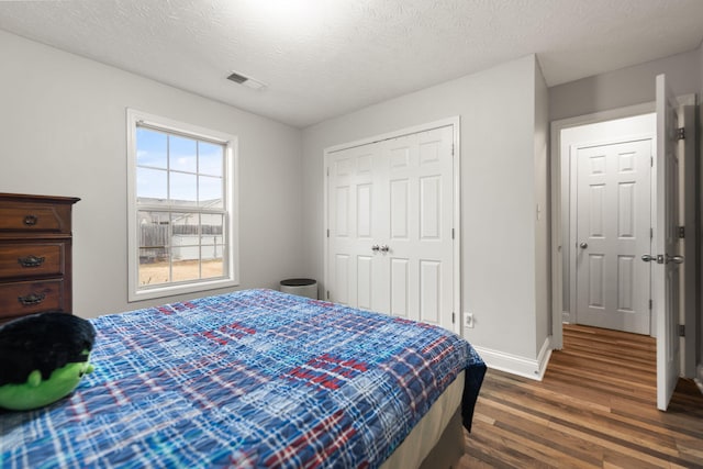 bedroom featuring dark wood-type flooring, a textured ceiling, and a closet