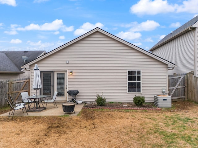 back of property featuring central AC unit, a fire pit, a patio, and a lawn