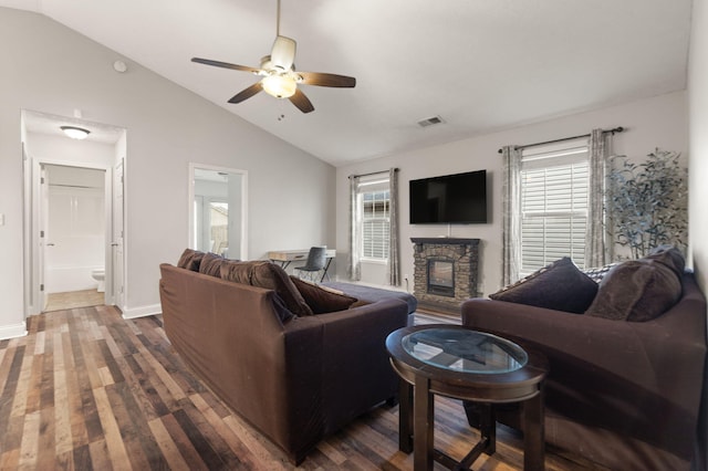 living room featuring lofted ceiling, plenty of natural light, dark wood-type flooring, and a stone fireplace