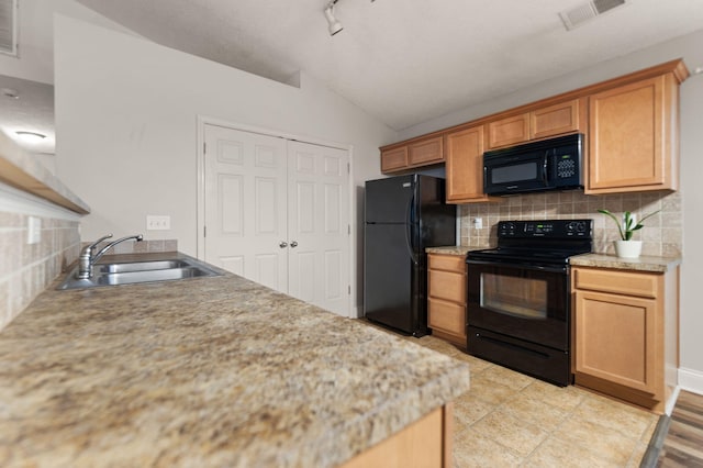 kitchen featuring lofted ceiling, sink, decorative backsplash, light tile patterned floors, and black appliances