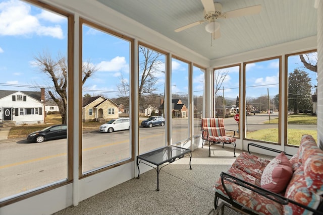 sunroom / solarium with a healthy amount of sunlight, a residential view, and a ceiling fan