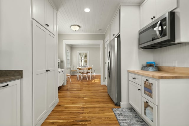 kitchen featuring butcher block countertops, white cabinetry, baseboards, appliances with stainless steel finishes, and light wood finished floors