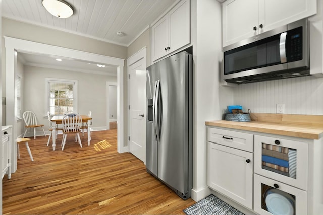 kitchen featuring white cabinets, light wood-style flooring, ornamental molding, stainless steel appliances, and wooden counters