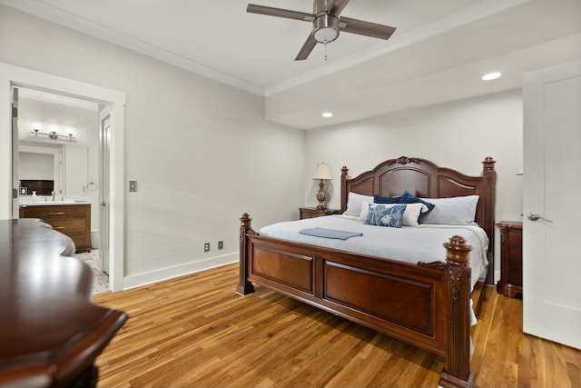 bedroom with connected bathroom, light wood-style flooring, a sink, baseboards, and crown molding