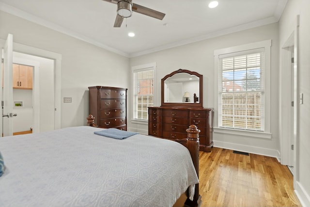 bedroom featuring baseboards, light wood finished floors, visible vents, and crown molding