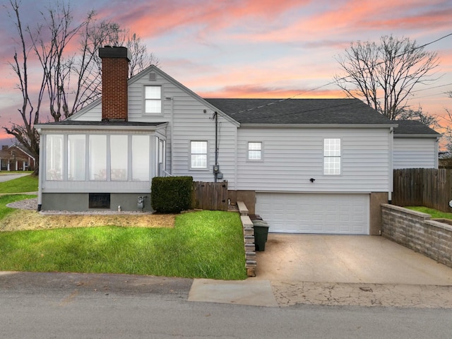 back of property featuring an attached garage, fence, a sunroom, concrete driveway, and a chimney