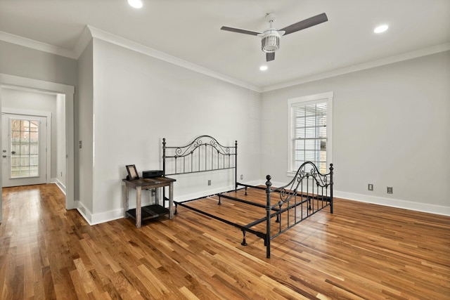 bedroom with crown molding, multiple windows, wood finished floors, and baseboards