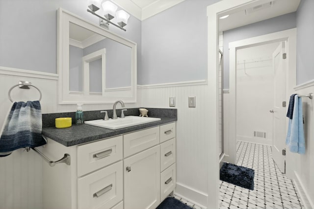 full bathroom featuring a spacious closet, wainscoting, vanity, and visible vents