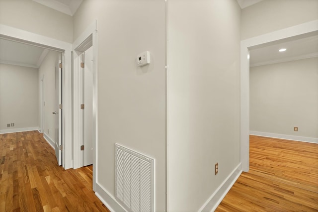 hall featuring ornamental molding, visible vents, baseboards, and wood finished floors