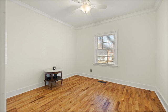 spare room featuring light wood-style floors, baseboards, visible vents, and ornamental molding