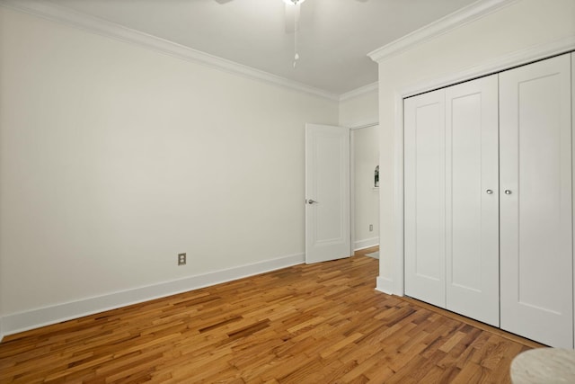 unfurnished bedroom featuring a closet, ornamental molding, a ceiling fan, light wood-type flooring, and baseboards