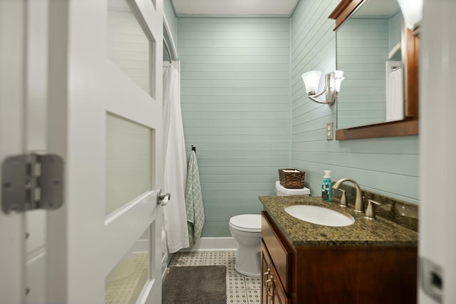 bathroom featuring toilet, curtained shower, vanity, and wooden walls