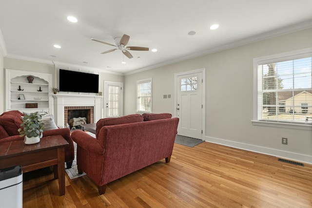 living room featuring visible vents, crown molding, light wood finished floors, and baseboards