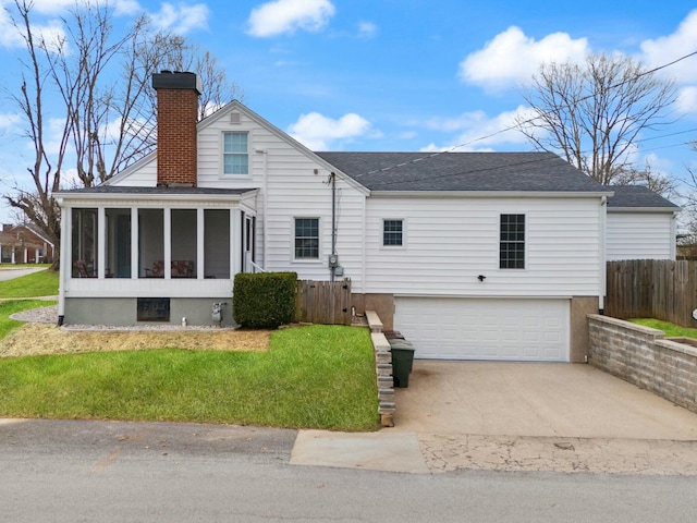 back of house with concrete driveway, a sunroom, a chimney, an attached garage, and fence