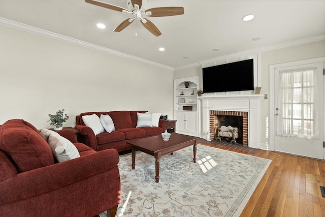 living room with ornamental molding, wood-type flooring, and a fireplace