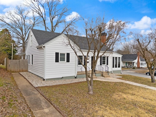 bungalow featuring a chimney, crawl space, covered porch, fence, and a front lawn