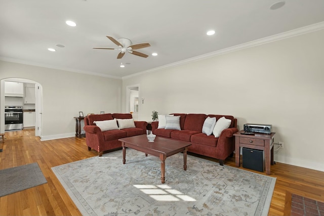 living area with light wood-style flooring, arched walkways, and ornamental molding