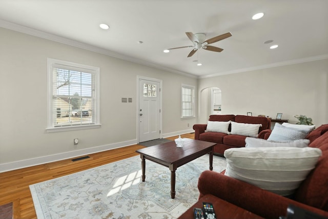 living area with baseboards, visible vents, arched walkways, and wood finished floors