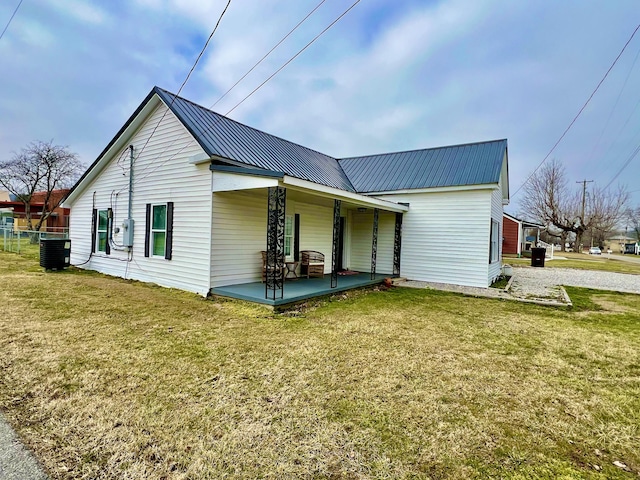 view of side of property featuring a yard, central AC unit, and covered porch