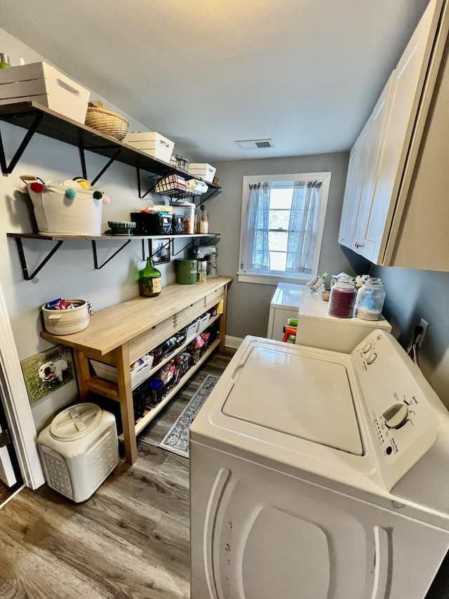 washroom featuring cabinets, separate washer and dryer, and dark hardwood / wood-style floors