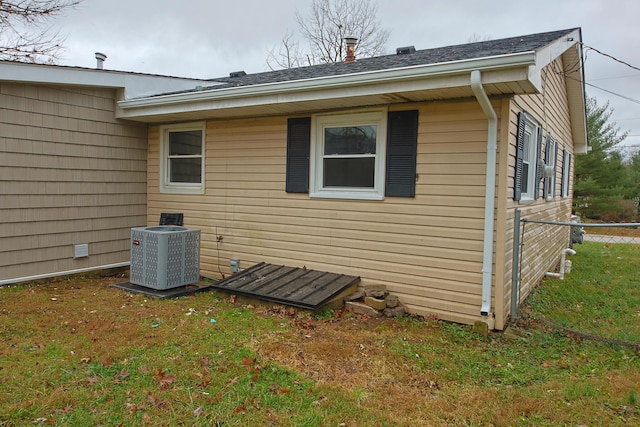 view of property exterior with cooling unit and a lawn