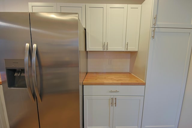 kitchen featuring butcher block countertops, stainless steel fridge with ice dispenser, tasteful backsplash, and white cabinets