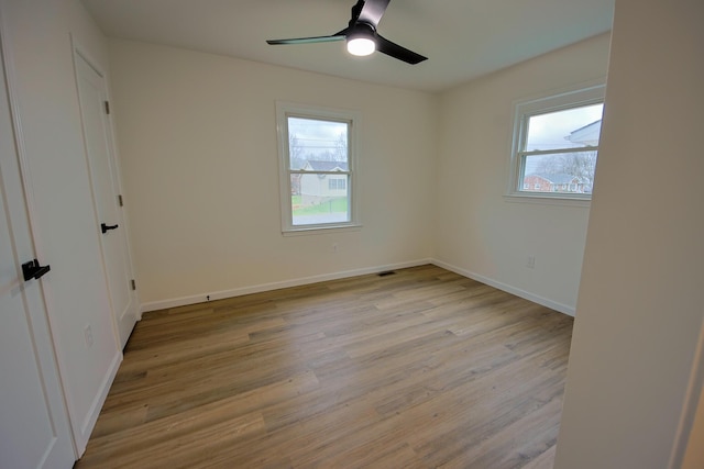 empty room featuring ceiling fan, a healthy amount of sunlight, and light wood-type flooring