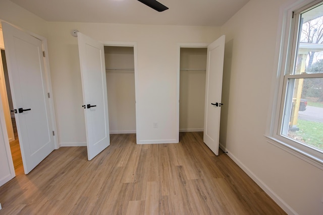 unfurnished bedroom featuring light hardwood / wood-style floors and two closets