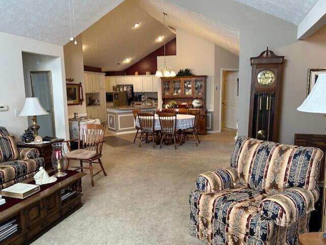 carpeted living room with high vaulted ceiling and a textured ceiling