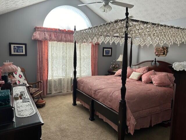 carpeted bedroom with ceiling fan, vaulted ceiling, and a textured ceiling