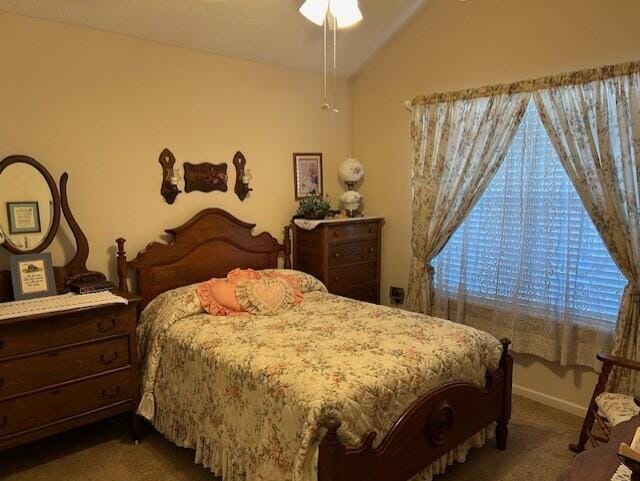 bedroom with ceiling fan, lofted ceiling, and dark carpet