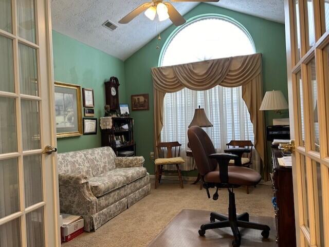 carpeted home office featuring vaulted ceiling, ceiling fan, a textured ceiling, and french doors