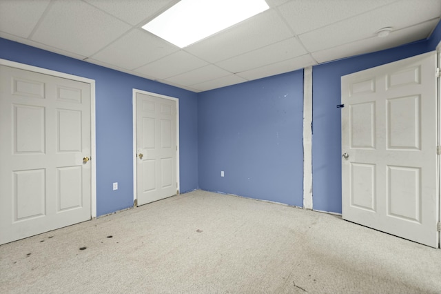 unfurnished bedroom featuring a drop ceiling and carpet