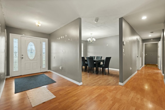 entryway with wood-type flooring and an inviting chandelier