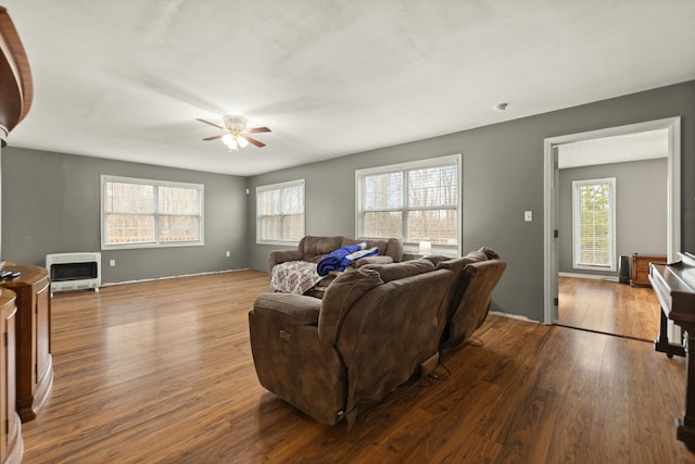 living room with heating unit, light hardwood / wood-style flooring, and ceiling fan